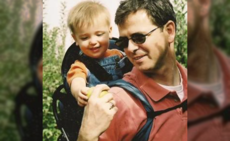 Feature image Man in nature with a toddler in a carrier on his back.