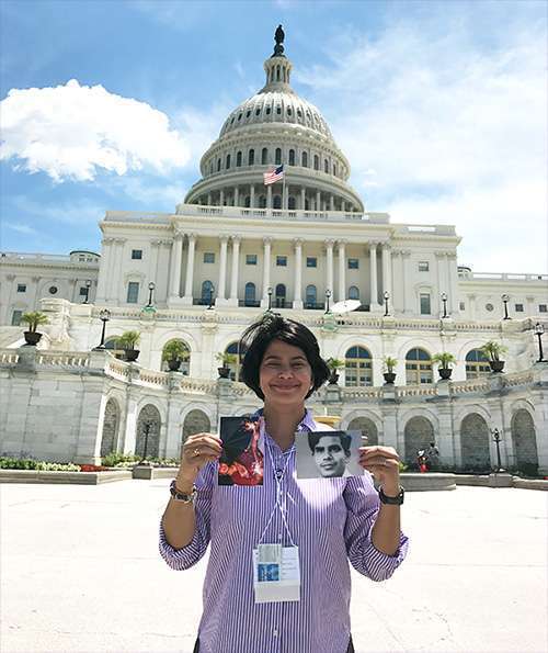 Pancreatic cancer advocate smiles in front of the U.S. Capitol building holding up photos of her loved ones