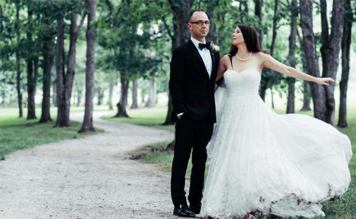 Joy Barber in a white wedding dress posing with her husband, Steve.