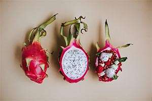 Sliced dragon fruits with a vibrant red skin and sweet white flesh speckled with black seeds.