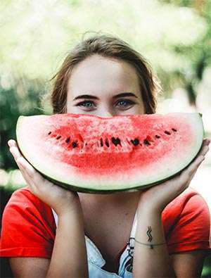 Young woman prepares to eat watermelon as fruits are part of a healthy diet.