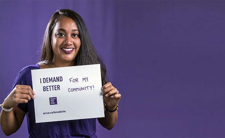 Volunteer holds a sign saying why she Demands Better for pancreatic cancer patients
