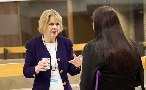 Feature image Barbara Kenner, PhD, speaks with a conference attendee about pancreatic cancer research