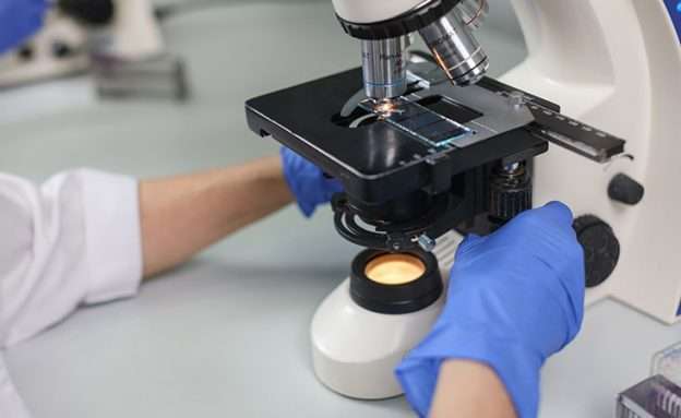 Feature image Researcher looks at microscope to study new pancreatic cancer treatment combination
