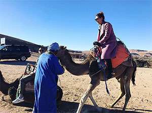 Pancreatic cancer survivor and performer Christina Helena laughs on vacation while riding a camel