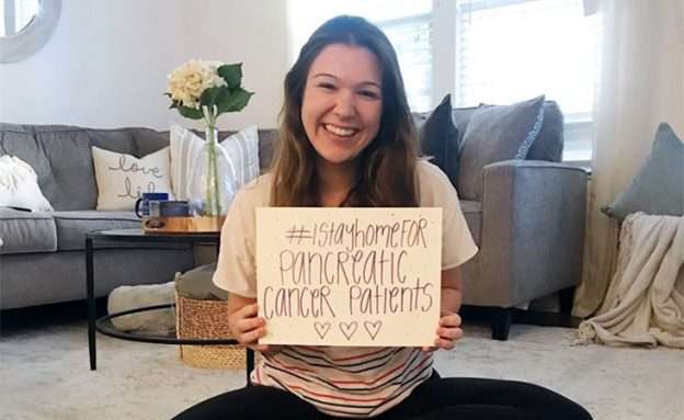 Feature image Young woman at home holding sign, “I stay home for pancreatic cancer patients” during pandemic