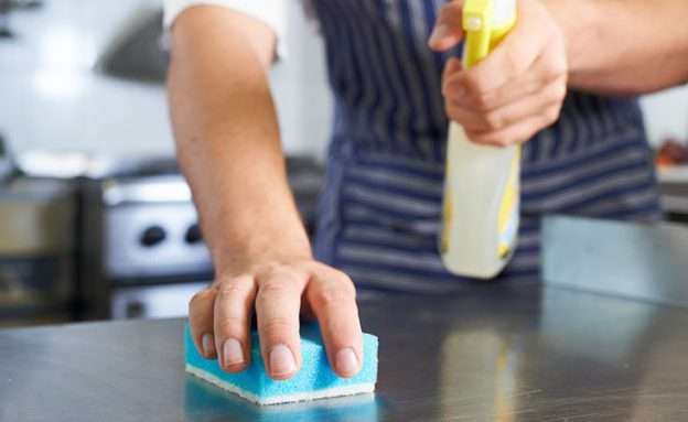Feature image Caregiver for pancreatic cancer patient disinfects kitchen counter before preparing a meal