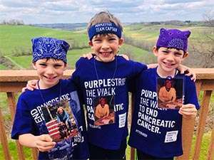 Three boys on pancreatic cancer walk wearing purple PanCAN tees with photos of their grammy