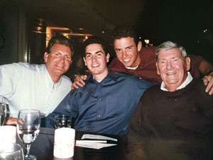 Family photo of grandfather, father and two adult sons at restaurant