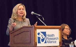 Middle-aged Caucasian businesswoman speaking to an audience at a professional conference.