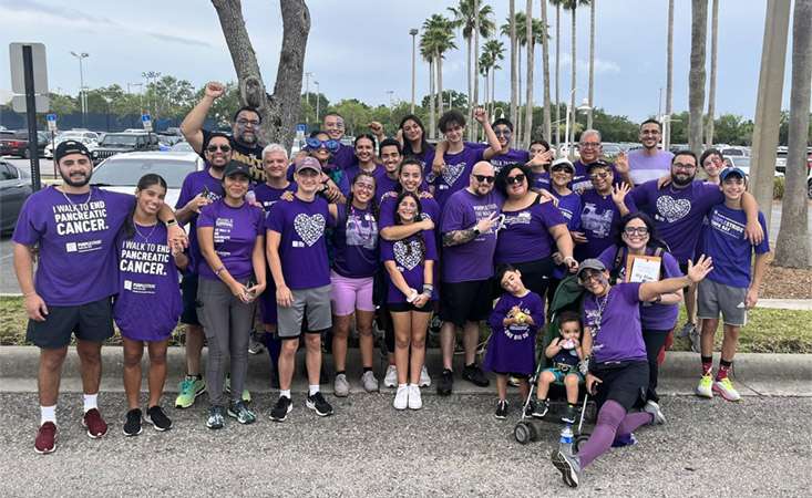 Feature image Thirty people posing for a group shot wearing PanCAN PurpleStride T-shirts.