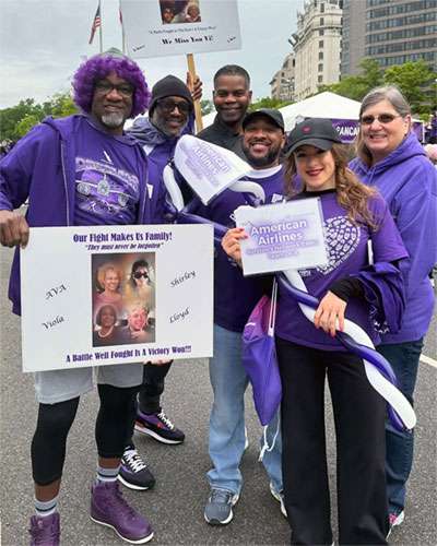 Six people holding signs with pictures of lost loved ones at PanCAN PurpleStride 2024.