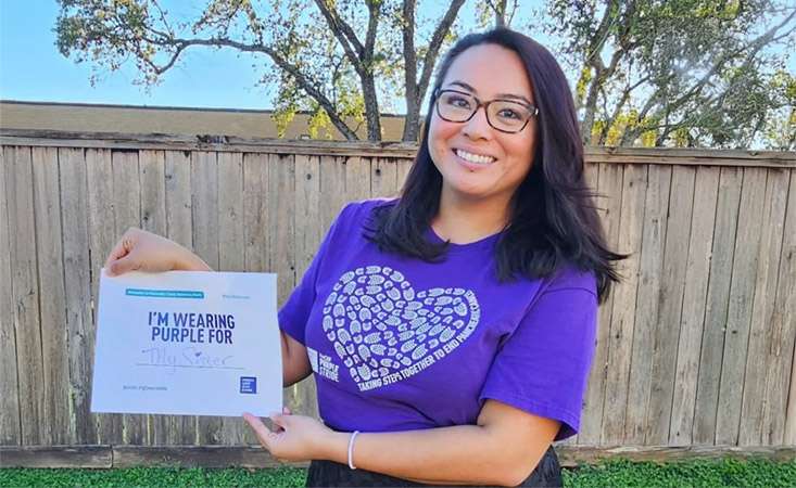 Feature image Woman wearing a PurpleStride t-shirt holding a sign saying she’s wearing purple for her sister.