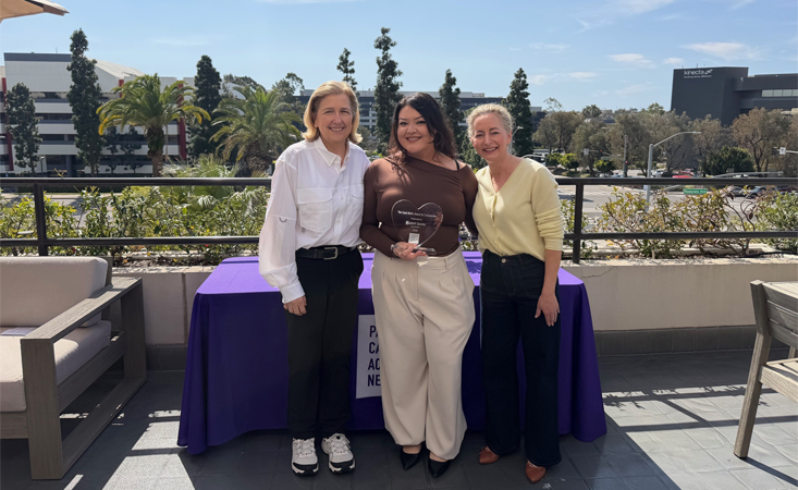 Feature image Three women standing outdoors. The woman in the middle is holding an award.